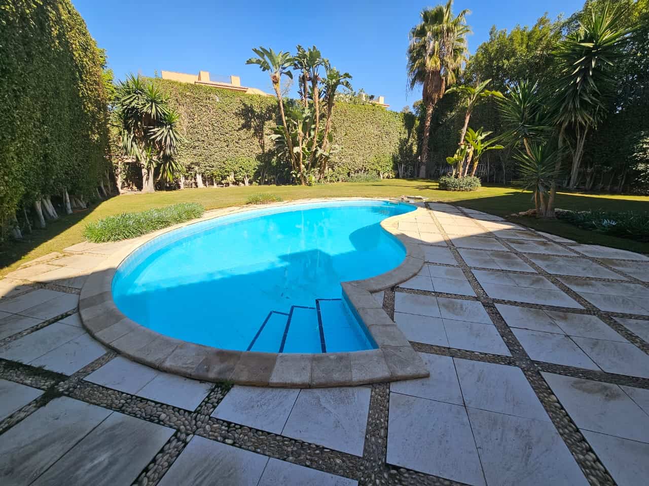 Swimming pool in a lush garden at Maadi Cairo Egypt luxury apartment complex, outdoor relaxation spot.