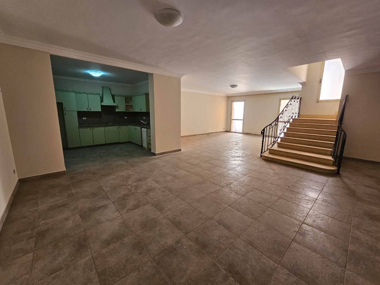 Spacious living room with open-plan kitchen and staircase in a modern apartment in Maadi, Cairo.