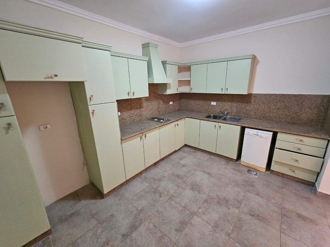 Bright green kitchen cabinets with granite countertops in a modern Cairo apartment.