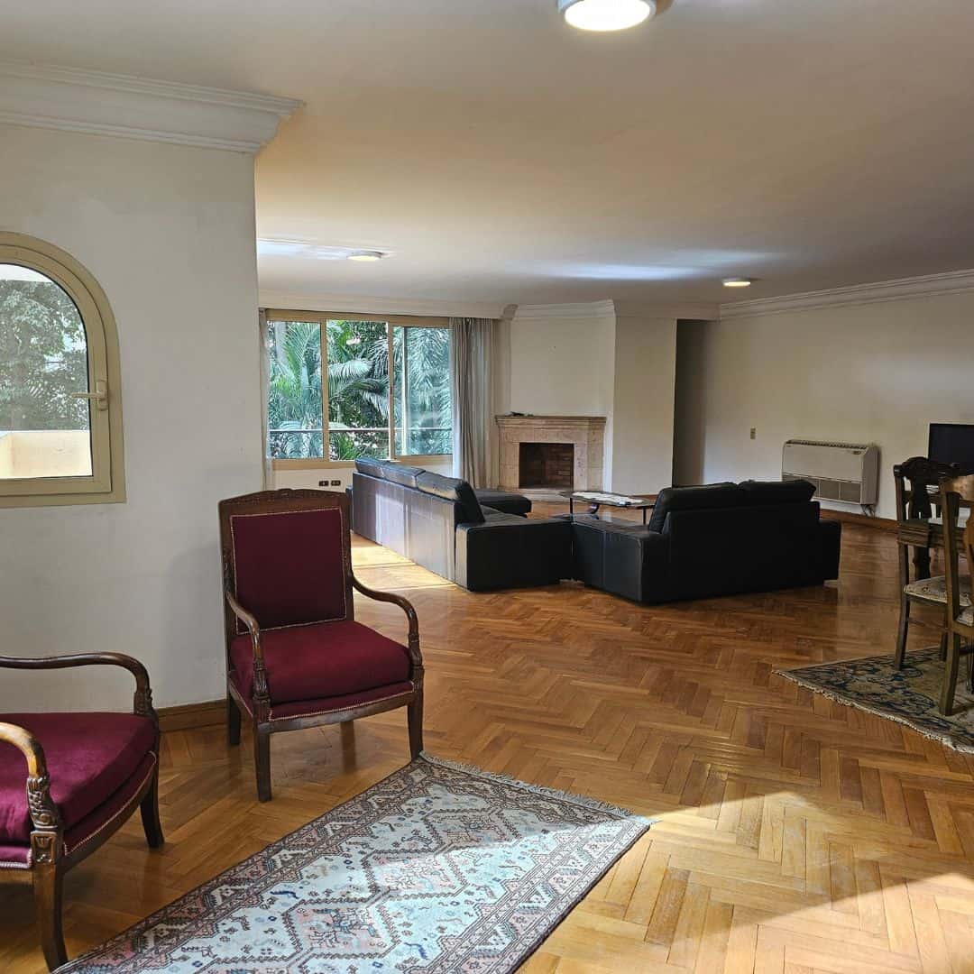 Spacious living room with large windows, wooden flooring, and cozy fireplace in Maadi Cairo apartments.