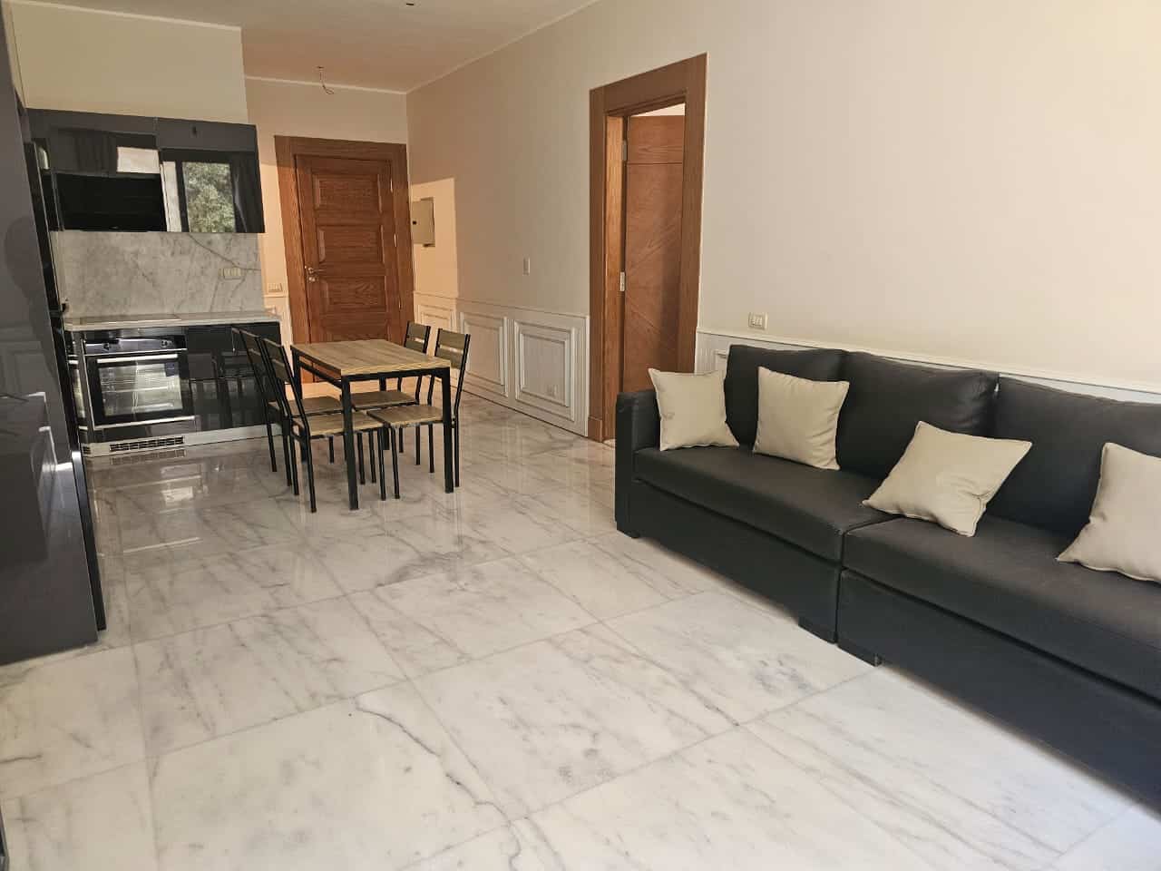 Modern apartment living room in Maadi, Cairo with sleek black sofa and marble flooring.