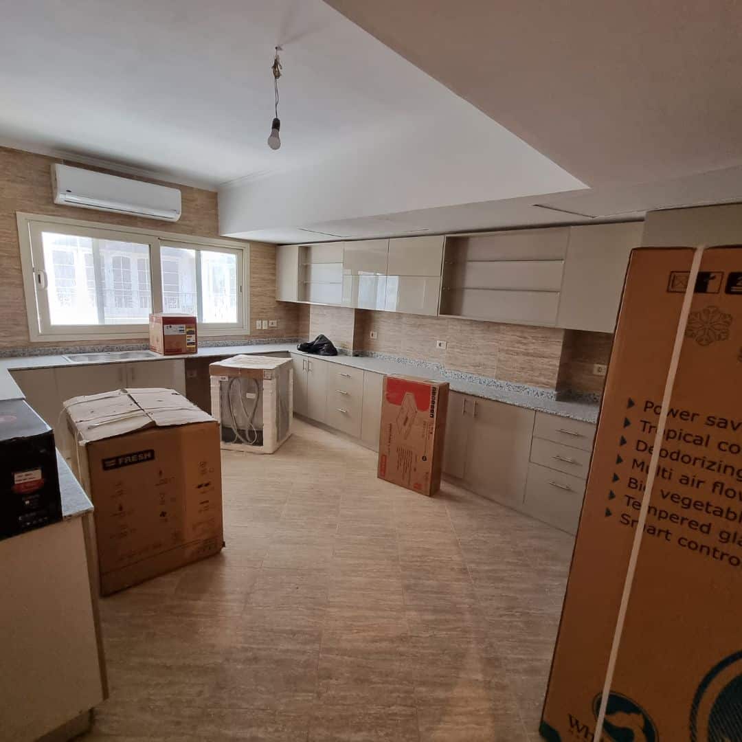 Modern apartment kitchen in Maadi Cairo with new cabinetry and large window for natural light.