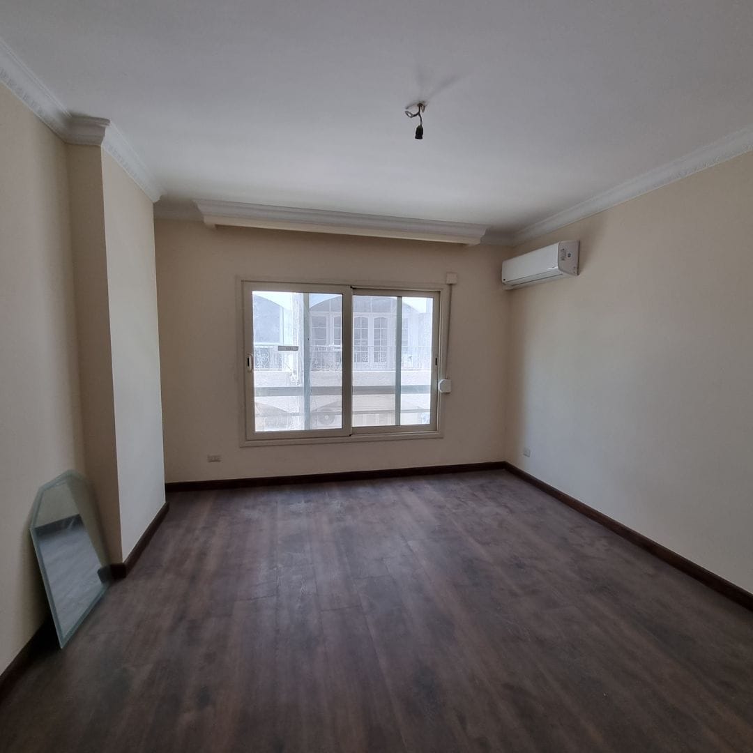 Bright spacious apartment in Maadi Cairo with large window, air conditioning, and neutral decor.