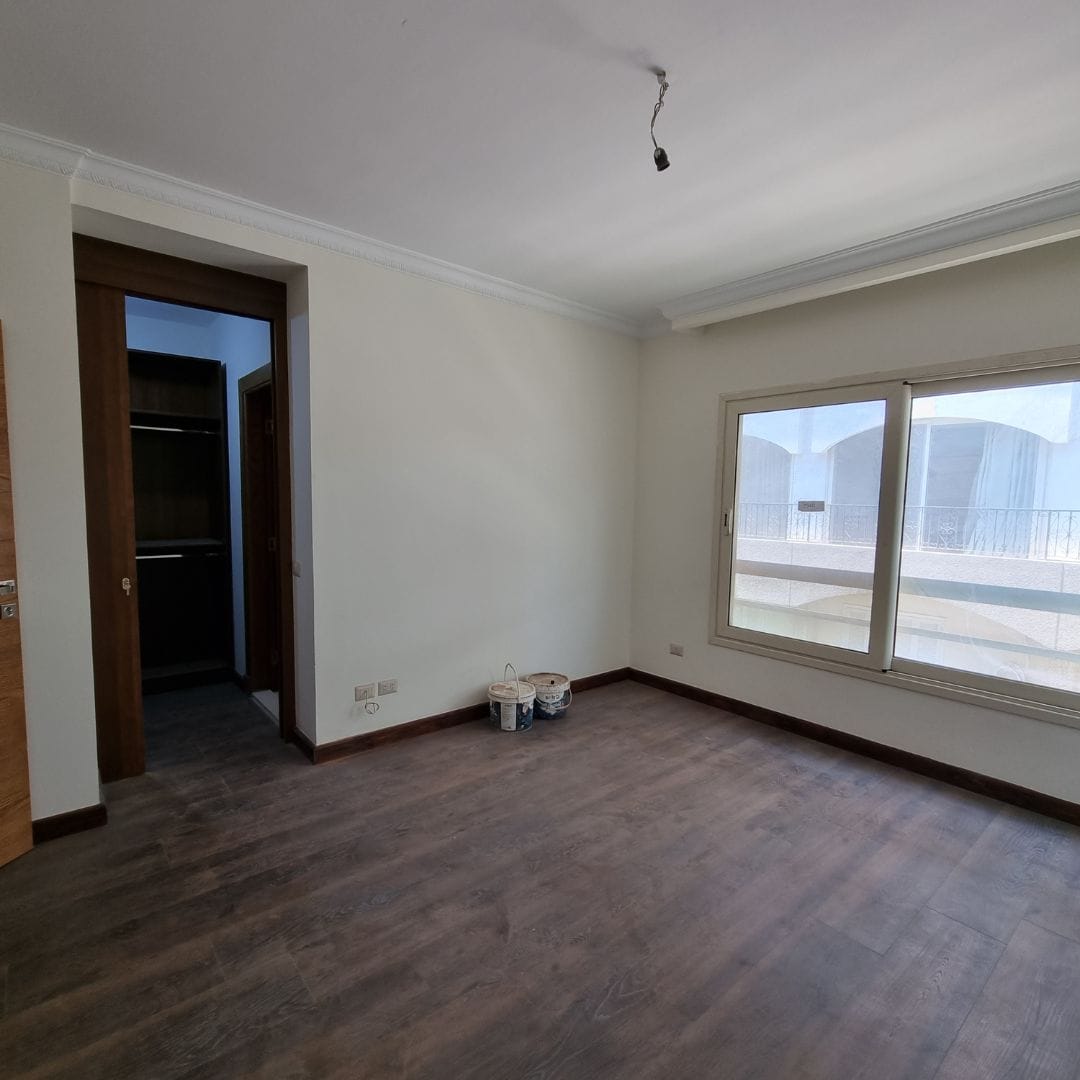 Modern unfurnished apartment interior in Maadi Cairo for rent with large window and wooden flooring.