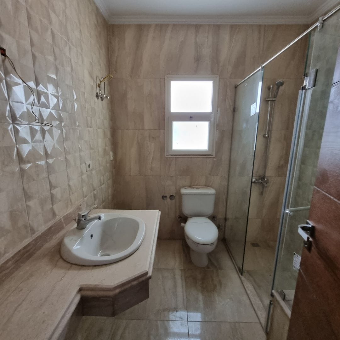 Modern bathroom with shower, toilet, and sink in Maadi Cairo apartment for rent.