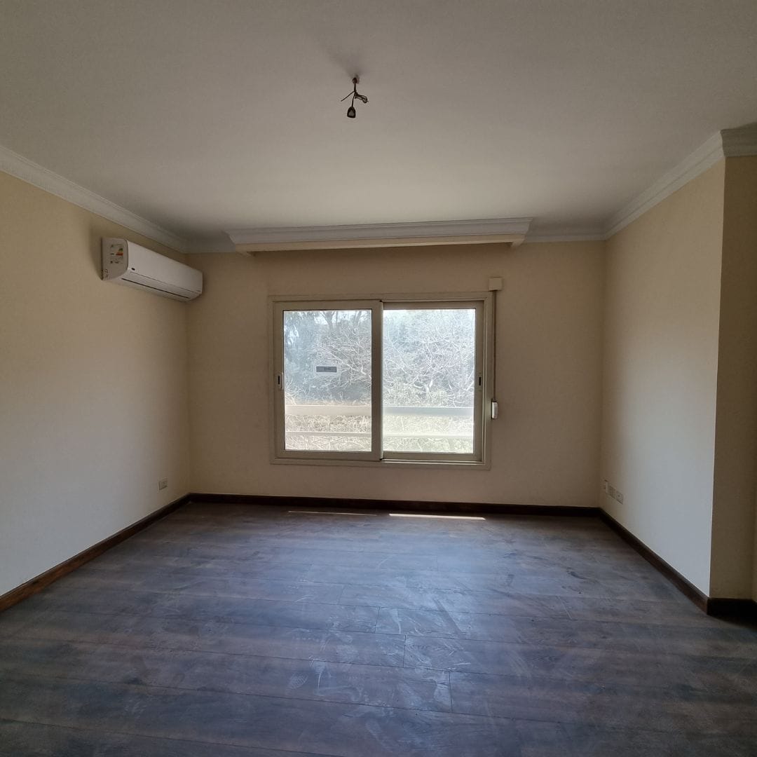 Spacious empty living room in Maadi Cairo apartment with large window and air conditioning unit.