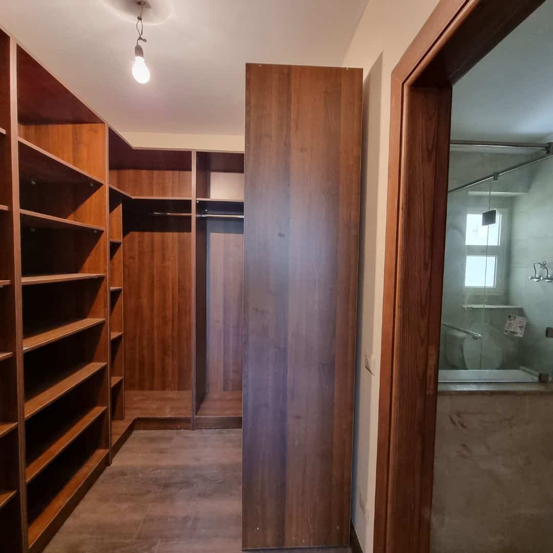 Modern wooden walk-in closet with ample shelves and storage space in Maadi Cairo Apartments.
